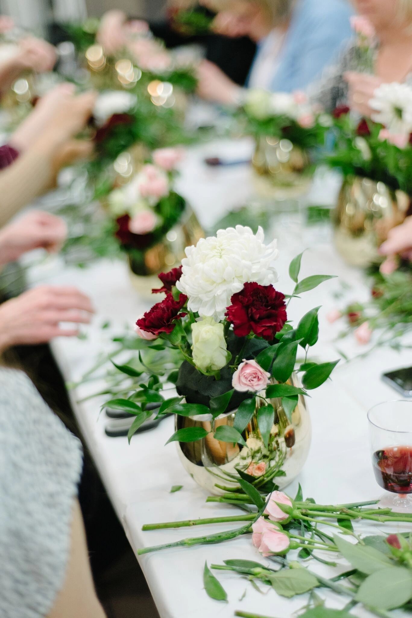 A finished arrangement of white and burgundy roses in a gold vase