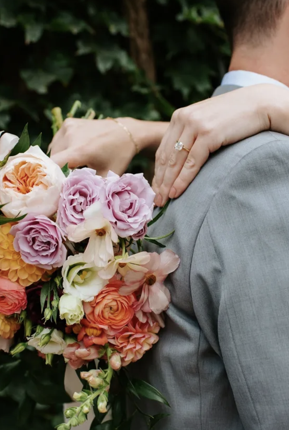 Victoria’s arms around Liam’s shoulders with her colourful bouquet of garden roses, ranunculus and cosmos