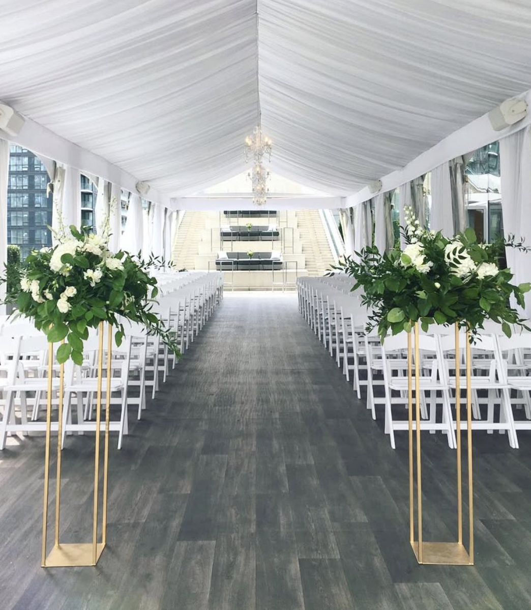 Tented rooftop ceremony at Malaparte with greenery and white floral arrangements on gold stands