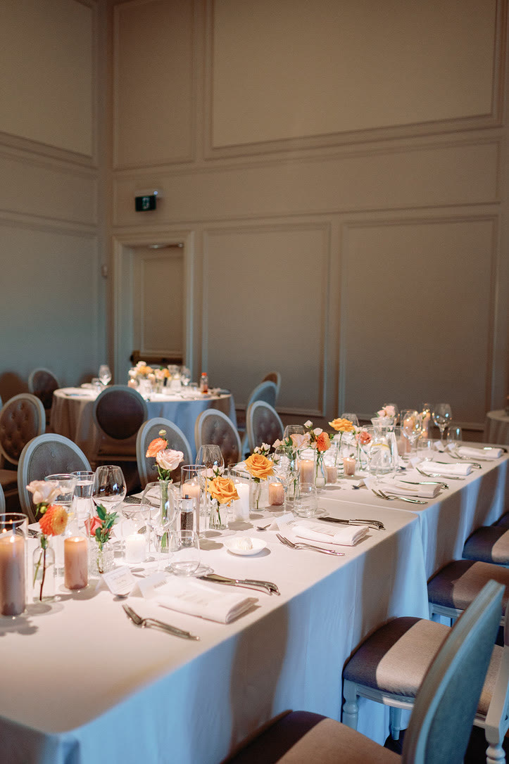 Reception table with bud vases of peach roses and candlelight at Arlington Estate