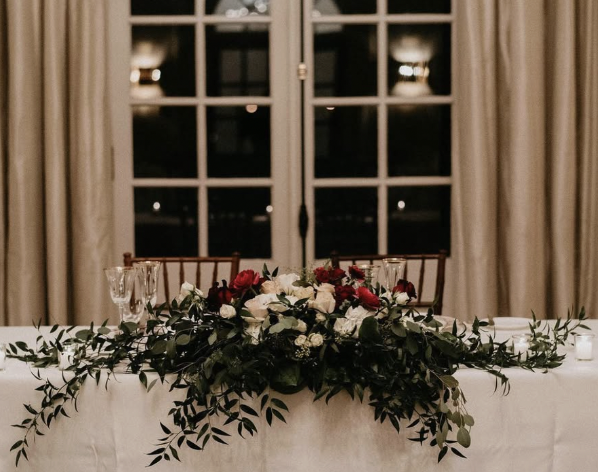 Lush burgundy rose and Italian ruscus garland cascading over the sweetheart table at Graydon Hall Manor