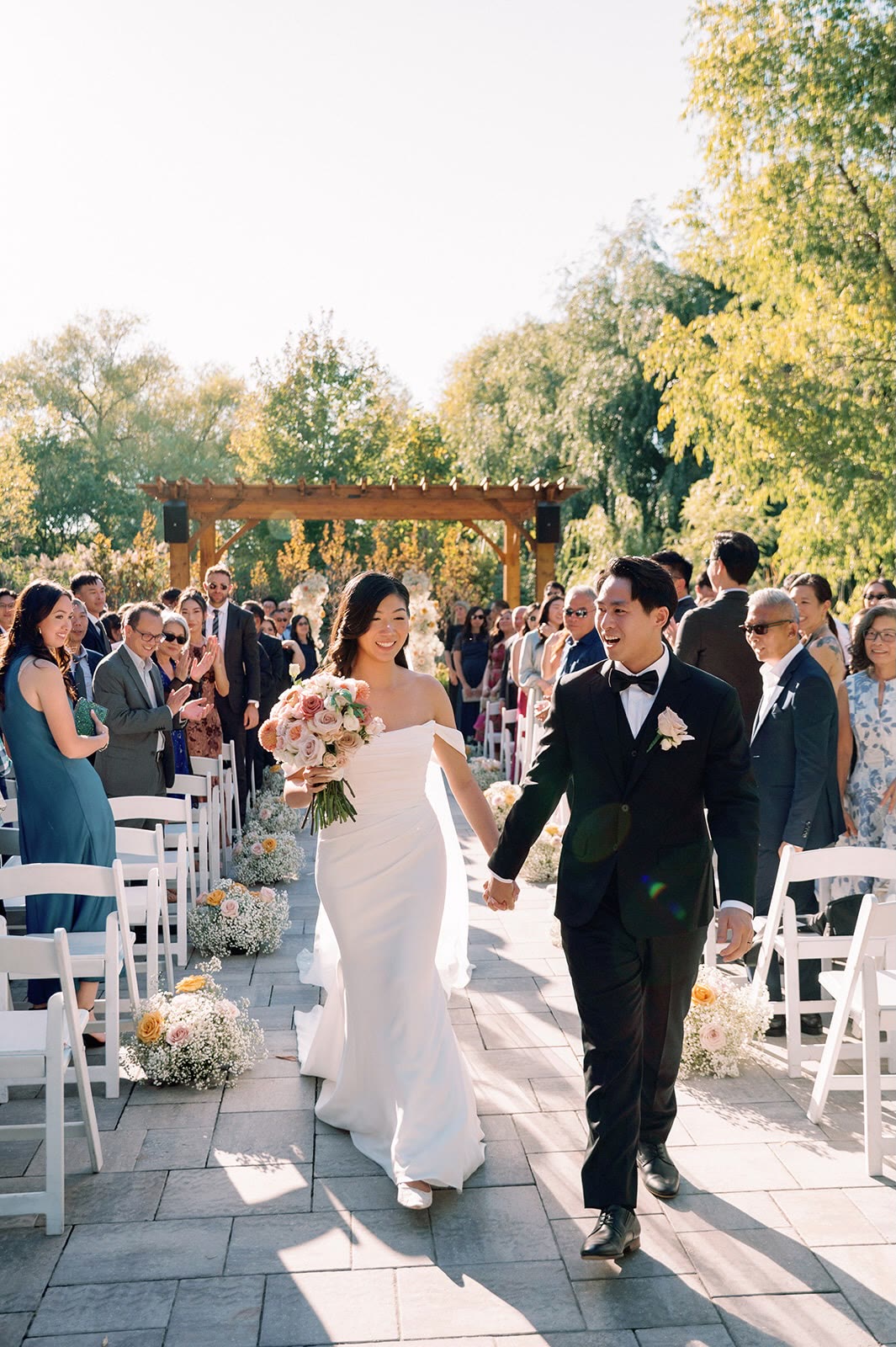 Kirsten and Hayden walking back down the aisle at Arlington Estate with her blush and peach bouquet