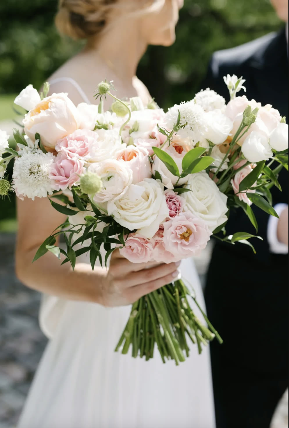 Bridget and Corey together outdoors with her garden-style bridal bouquet at Storys Building