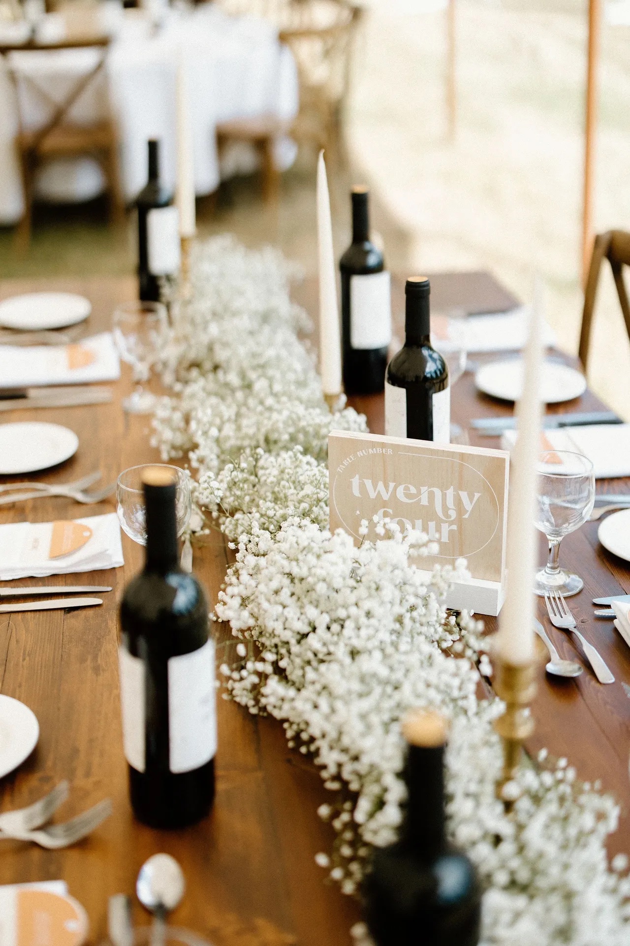 Baby’s breath table runner with taper candles, wine bottles and a table twenty-four sign