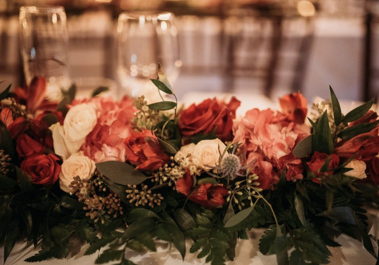 Close-up of red roses, coral hydrangea and ivory roses in a table garland