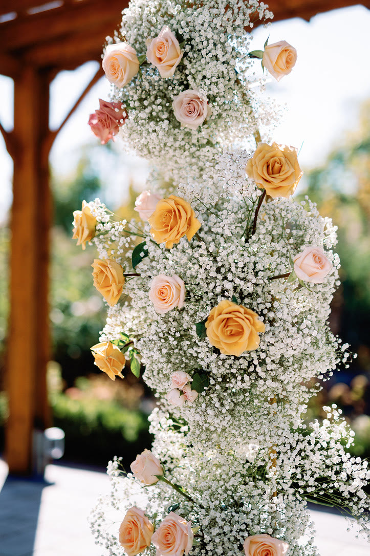 Baby’s breath ceremony pillar studded with peach, apricot and blush roses