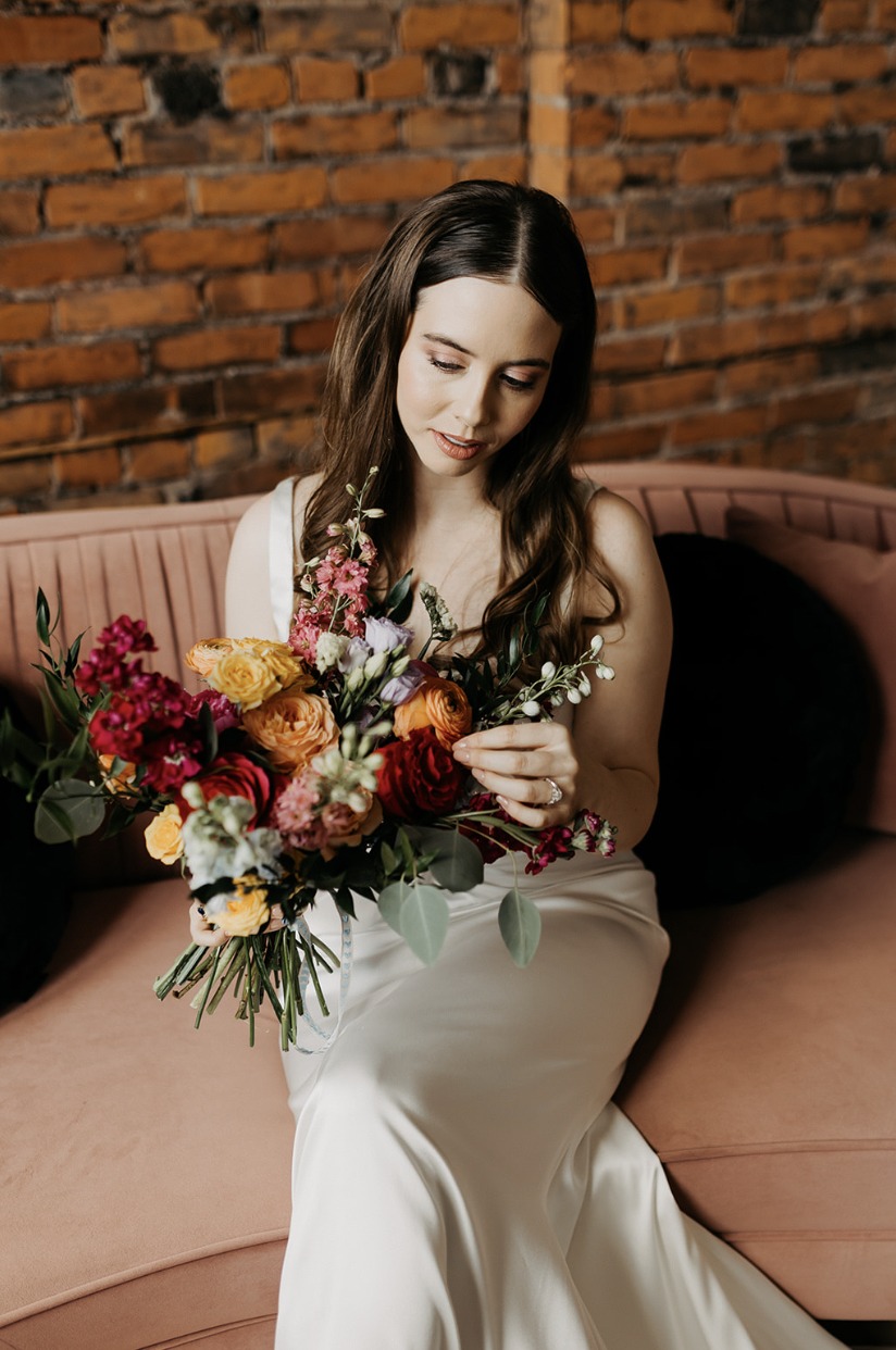 Lydia seated with her bouquet of red, yellow, orange and lavender flowers