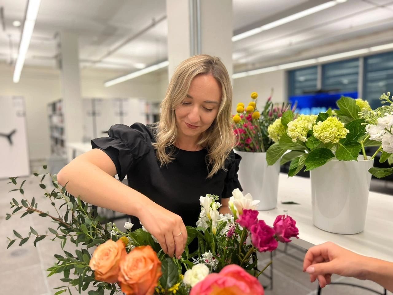 Kat demonstrating an arrangement of peach roses and pink peonies