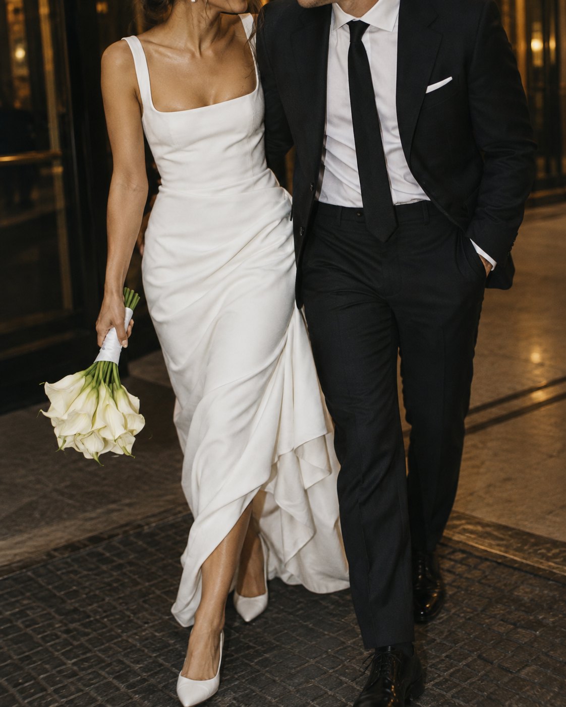 Newlyweds walking together in the evening, the bride carrying a calla lily bouquet