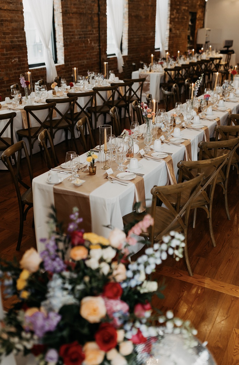 Lydia and Kaustav’s reception tables with colourful florals and candles at The Spice Factory