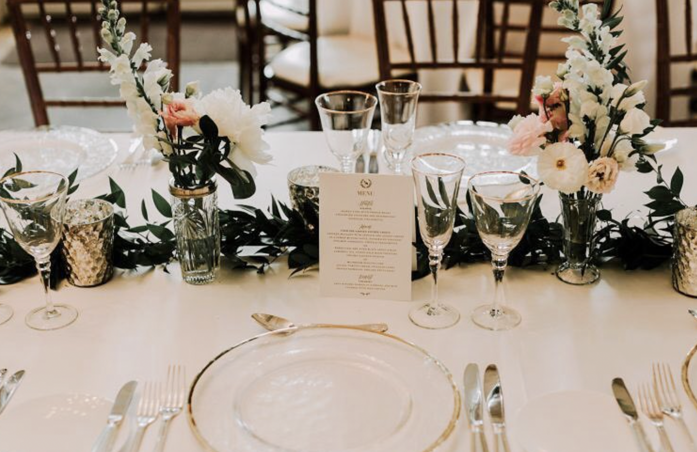 Bud vases of snapdragons, peonies and lisianthus on a ruscus runner with gold-rimmed glassware at Graydon Hall Manor