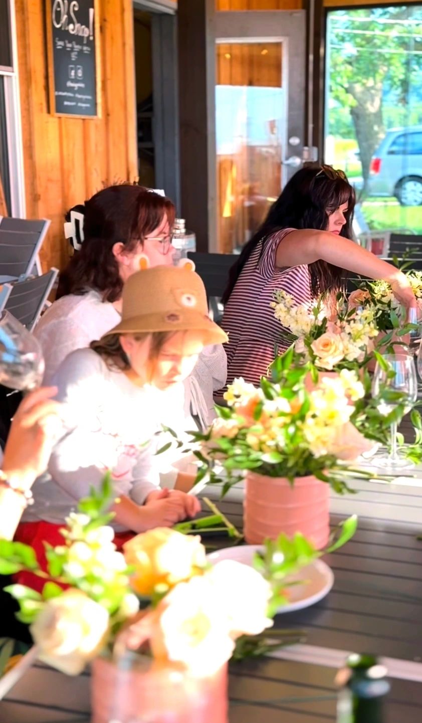 Guests arranging peach and ivory flowers in pink pots