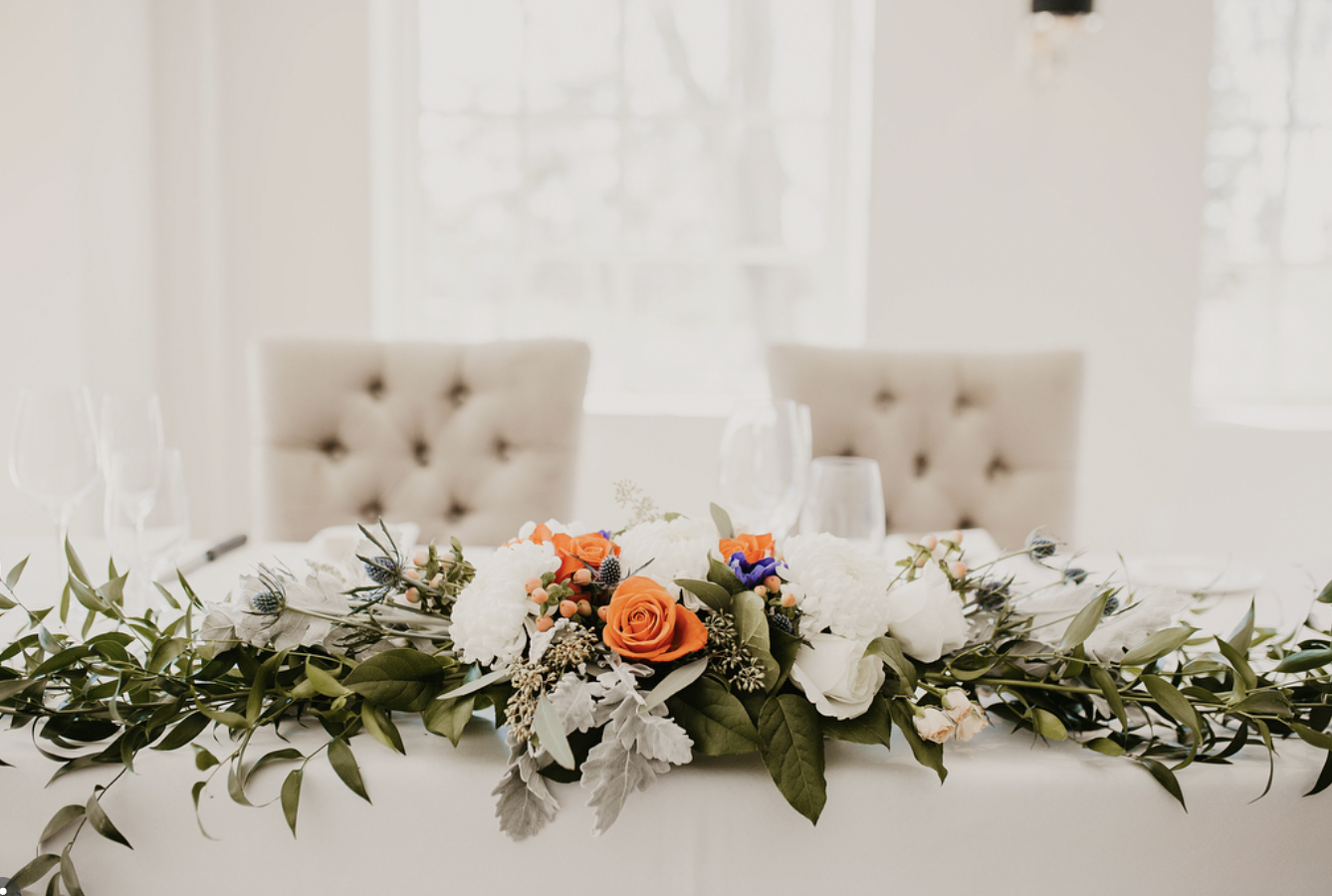 Head table garland with orange roses, white blooms and greenery at The Doctor’s House