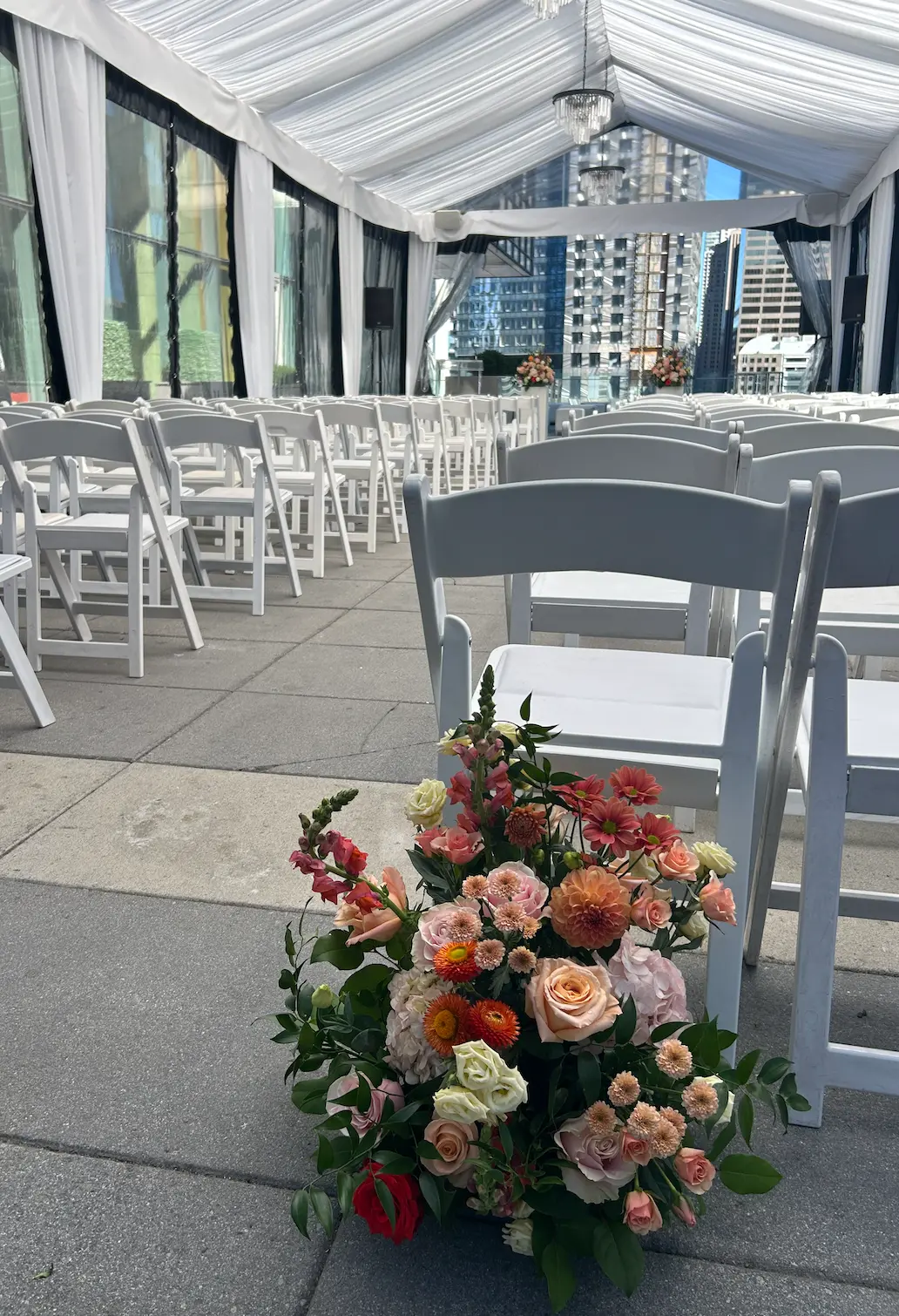 Peach, coral and blush aisle arrangement beside ceremony chairs on the Malaparte terrace